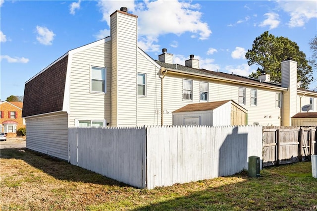 rear view of house with a lawn and a storage unit