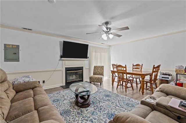 living room featuring ornamental molding, wood-type flooring, electric panel, and ceiling fan