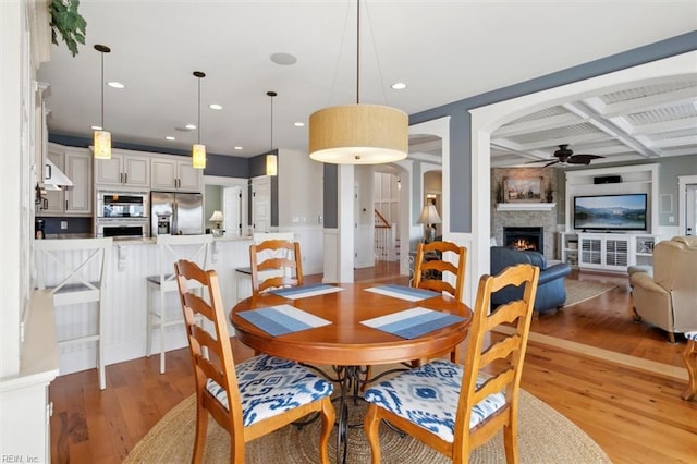 dining room featuring ceiling fan, coffered ceiling, hardwood / wood-style floors, and beam ceiling