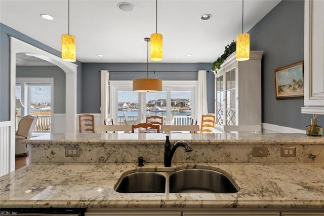 kitchen featuring pendant lighting, plenty of natural light, light stone countertops, and sink