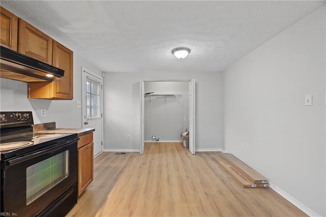 kitchen with black electric range oven, light hardwood / wood-style flooring, and a textured ceiling