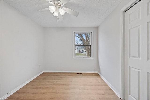 unfurnished room with ceiling fan, a textured ceiling, and light wood-type flooring