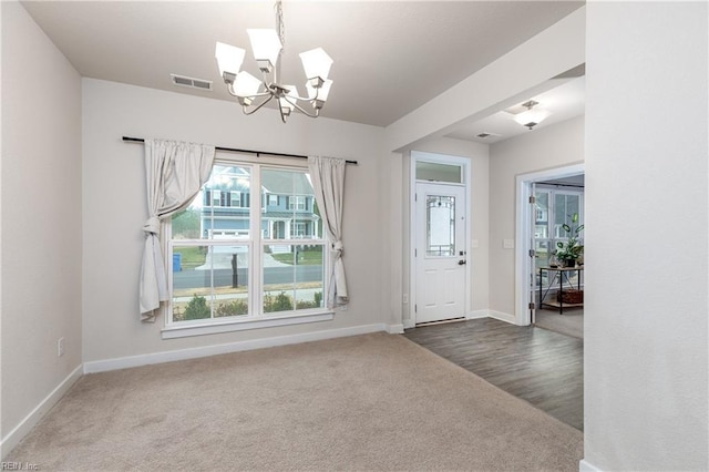 carpeted entrance foyer with an inviting chandelier