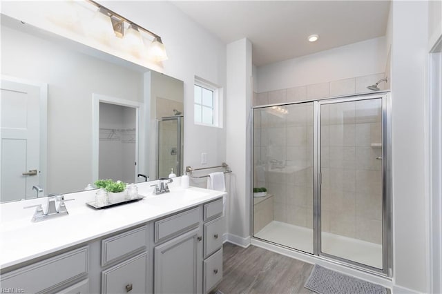 bathroom with wood-type flooring, a shower with shower door, and vanity