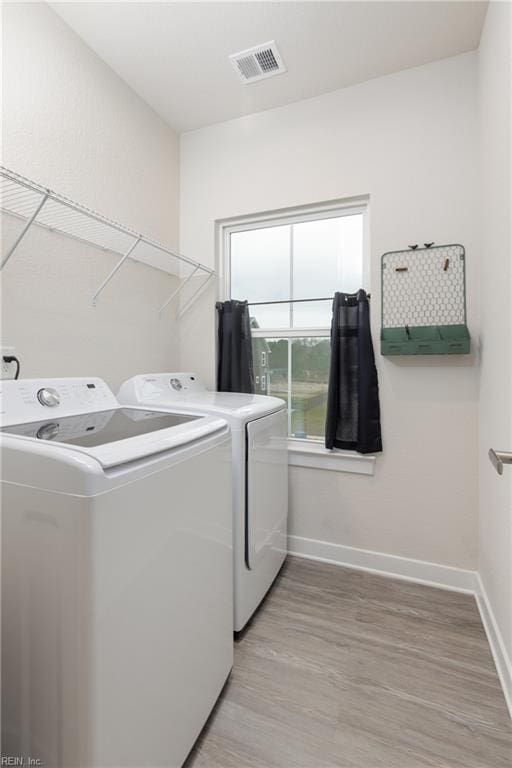 laundry area with washer and clothes dryer and light hardwood / wood-style floors