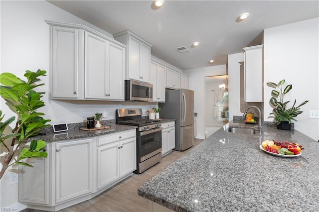 kitchen featuring dark stone countertops, sink, white cabinets, and appliances with stainless steel finishes