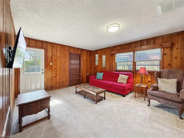 living room featuring wooden walls, light carpet, and a textured ceiling