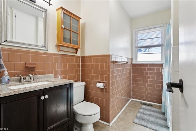 bathroom with vanity, toilet, tile patterned flooring, and tile walls