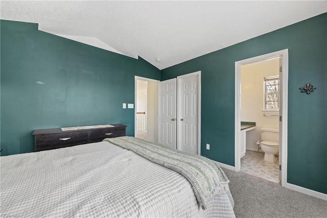 carpeted bedroom with lofted ceiling, a closet, and ensuite bathroom