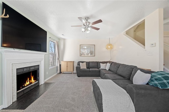 living room featuring dark carpet, a fireplace, and ceiling fan