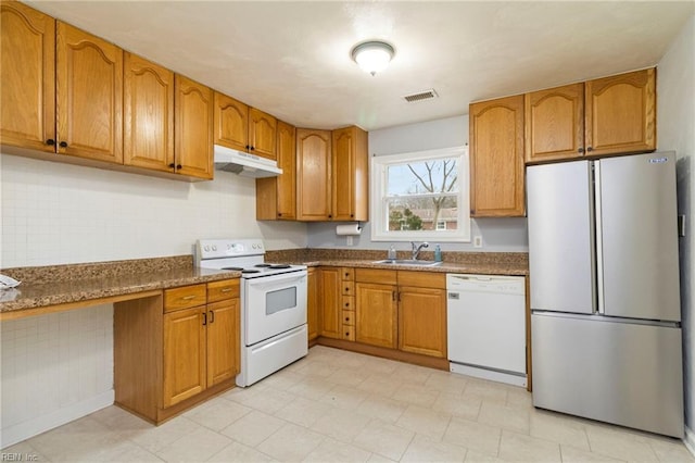 kitchen with sink, white appliances, and dark stone counters