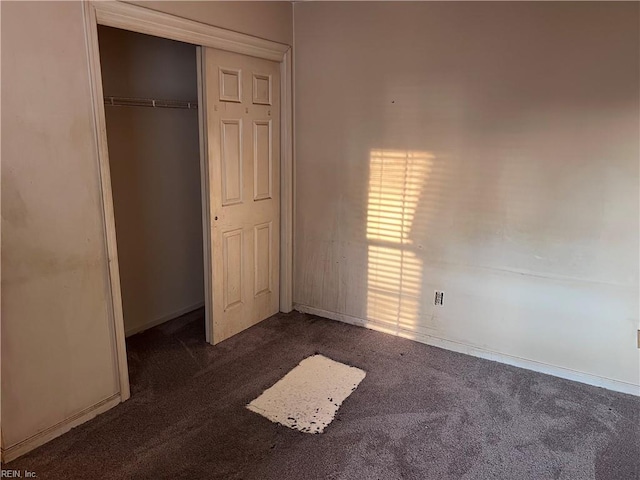 unfurnished bedroom featuring dark colored carpet and a closet