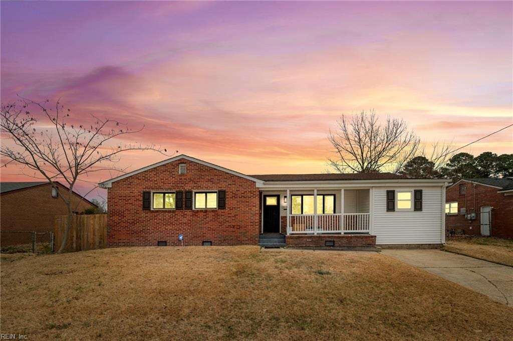 ranch-style home with covered porch and a lawn