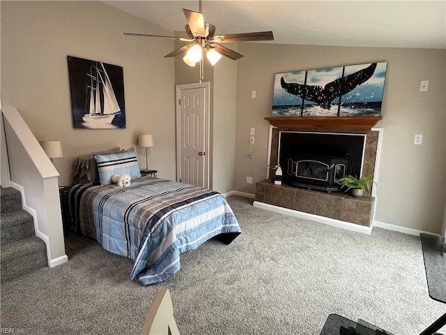 carpeted bedroom featuring a tiled fireplace, lofted ceiling, and ceiling fan