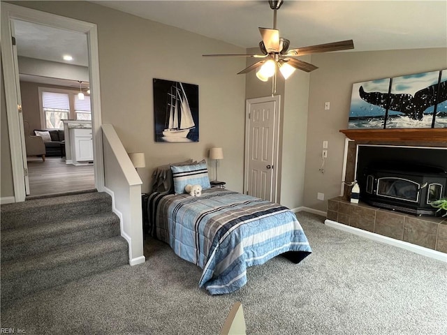 carpeted bedroom with a tile fireplace and ceiling fan