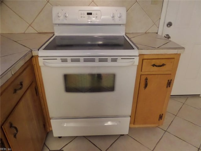 kitchen with backsplash, white electric range, and light tile patterned floors