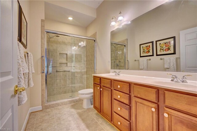 bathroom featuring tile patterned floors, vanity, toilet, and a shower with door