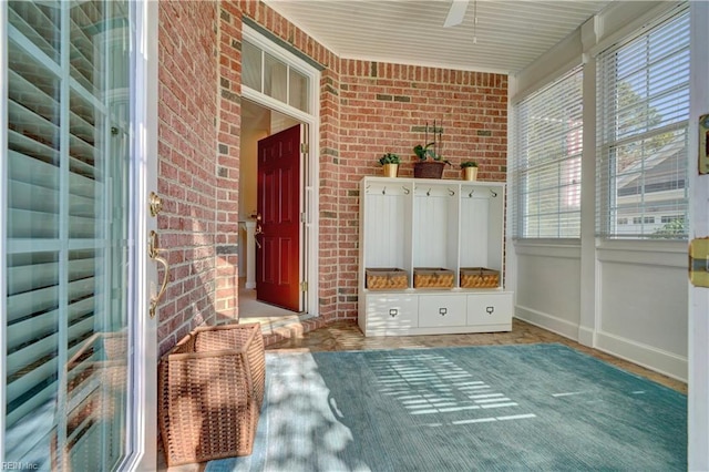 mudroom featuring ceiling fan and brick wall