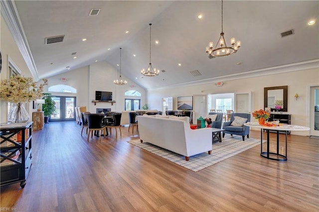 living room featuring high vaulted ceiling, a chandelier, and light hardwood / wood-style flooring