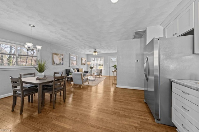 dining room with hardwood / wood-style flooring, ceiling fan with notable chandelier, and a healthy amount of sunlight