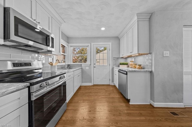 kitchen with stainless steel appliances, white cabinetry, dark hardwood / wood-style floors, and light stone counters