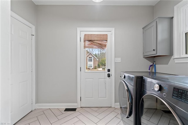 clothes washing area with cabinets, independent washer and dryer, and light parquet flooring