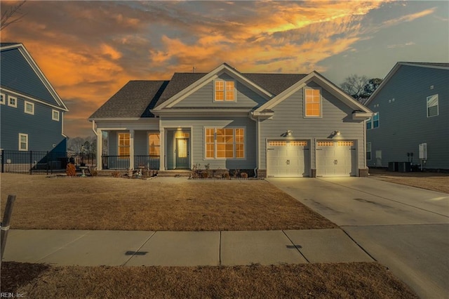 view of front facade with a garage, a yard, central AC unit, and covered porch