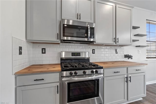 kitchen with stainless steel appliances, butcher block counters, wood-type flooring, and backsplash