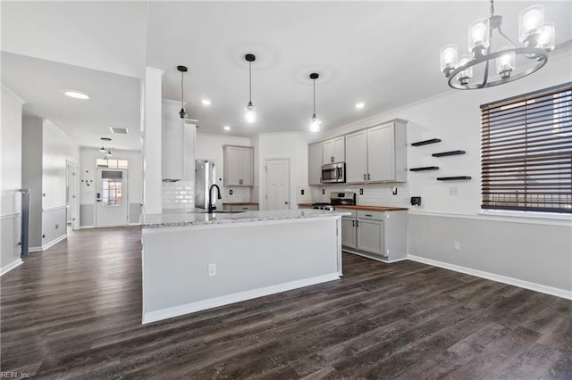 kitchen featuring light stone counters, hanging light fixtures, dark wood-type flooring, and stainless steel appliances