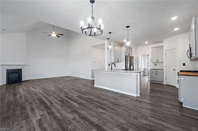 kitchen featuring pendant lighting, dark wood-type flooring, ceiling fan, appliances with stainless steel finishes, and decorative backsplash