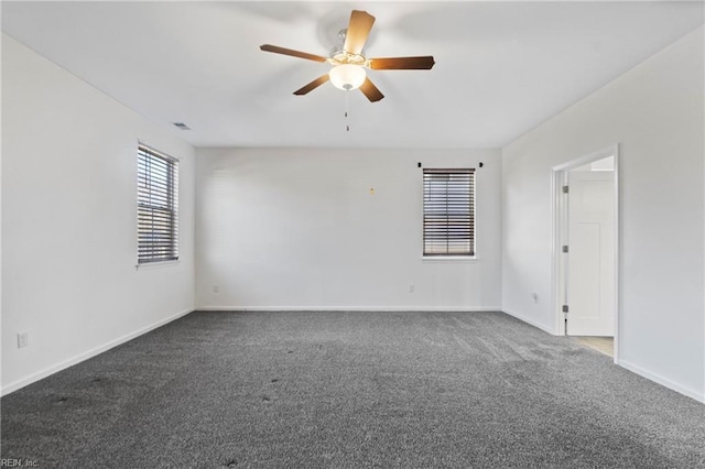 unfurnished room with dark colored carpet and ceiling fan