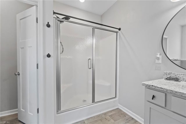 bathroom featuring vanity, wood-type flooring, and a shower with shower door