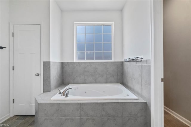 bathroom with wood-type flooring and tiled tub