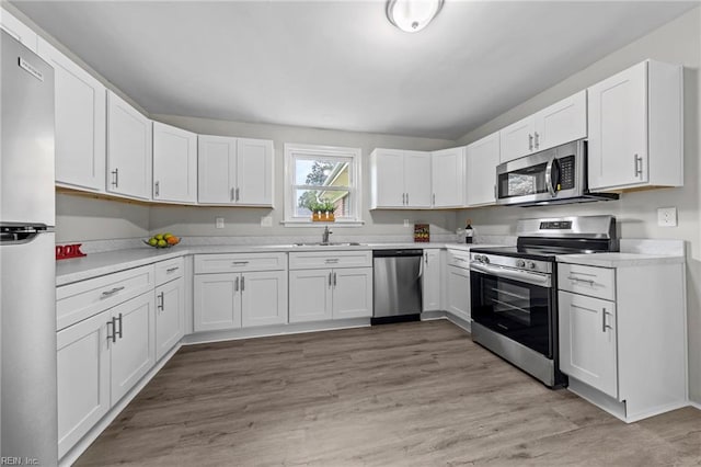 kitchen featuring stainless steel appliances, white cabinetry, sink, and light hardwood / wood-style floors