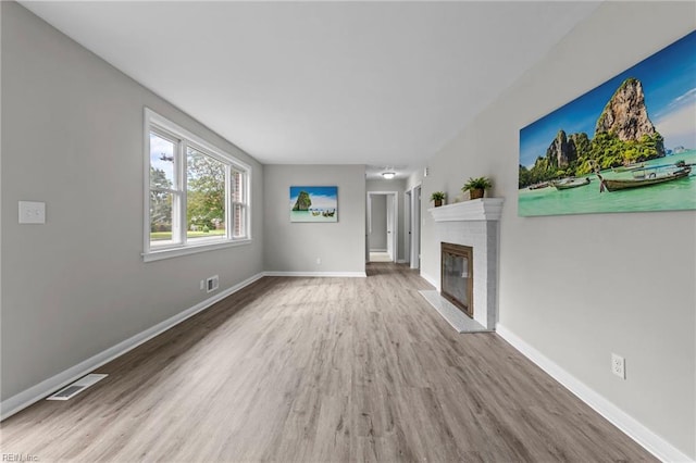 unfurnished living room with light hardwood / wood-style floors and a brick fireplace