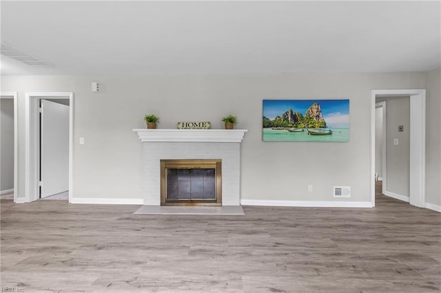 unfurnished living room featuring a brick fireplace and light hardwood / wood-style flooring