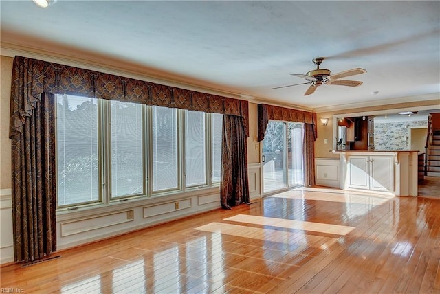 unfurnished living room featuring light hardwood / wood-style flooring, ornamental molding, and ceiling fan