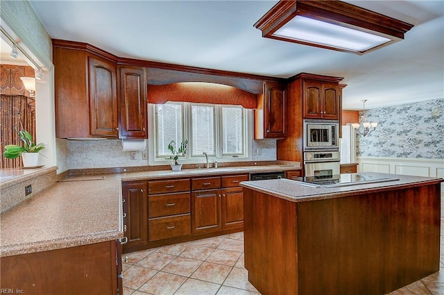 kitchen featuring sink, a chandelier, a kitchen island, pendant lighting, and stainless steel appliances