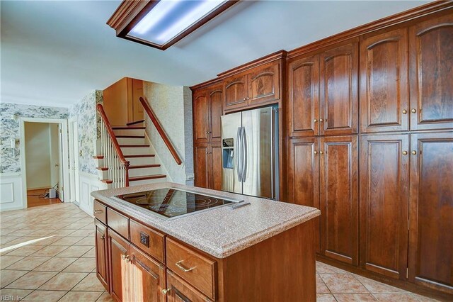 kitchen featuring black electric cooktop, light tile patterned floors, a center island, and stainless steel refrigerator with ice dispenser