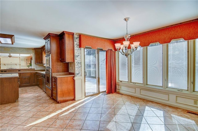 kitchen with pendant lighting, light tile patterned floors, an inviting chandelier, and appliances with stainless steel finishes