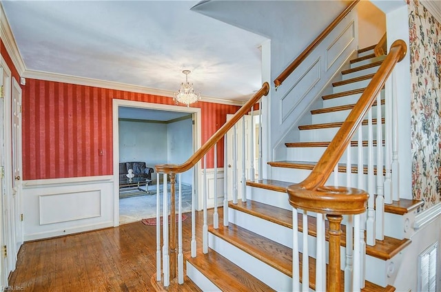 stairway featuring crown molding, a notable chandelier, and hardwood / wood-style flooring