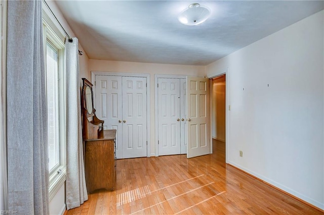 unfurnished bedroom featuring two closets and light hardwood / wood-style flooring