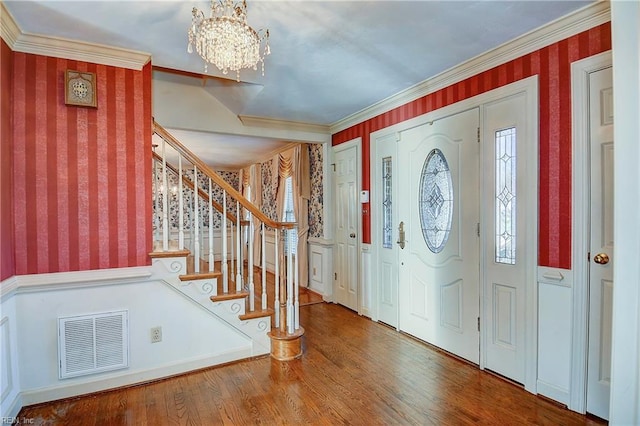 foyer entrance featuring crown molding, a healthy amount of sunlight, hardwood / wood-style floors, and a notable chandelier