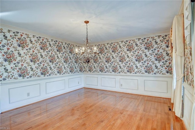 spare room featuring crown molding, a notable chandelier, and light hardwood / wood-style floors