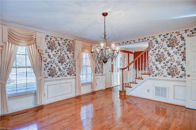 foyer entrance with ornamental molding, hardwood / wood-style floors, and an inviting chandelier