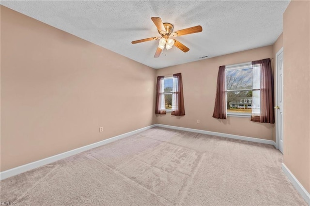 spare room featuring ceiling fan, light colored carpet, and a textured ceiling