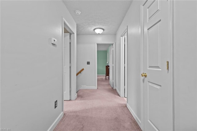 hallway featuring light carpet and a textured ceiling