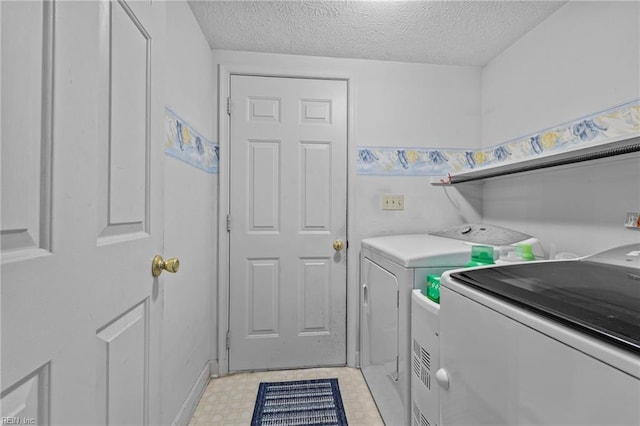 clothes washing area with washing machine and dryer and a textured ceiling