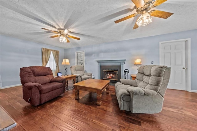 living room featuring ceiling fan, wood-type flooring, and a textured ceiling