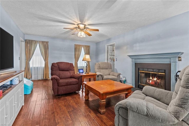 living room featuring ceiling fan, dark hardwood / wood-style floors, and a textured ceiling